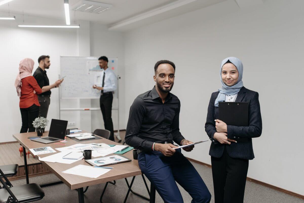 man in black shirt and woman in blue hijab holding clipboards