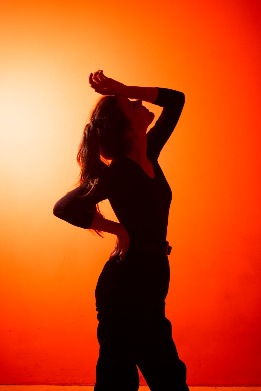 back lit silhouette of woman standing with arm raised